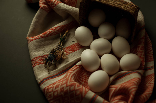 Białe jaja kurze, na tkaninie dekoracyjnej, w pięknym koszyku, przygotowanie do Wielkanocy - Zdjęcie, obraz