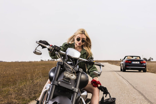 Een mooie jonge vrouw zitten op een motor zwart en chroom - Foto, afbeelding