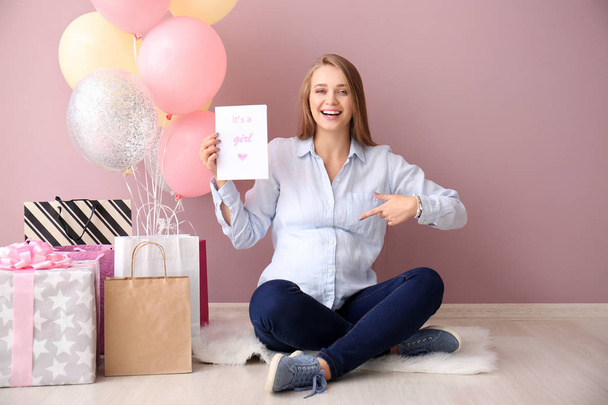Beautiful pregnant woman with baby shower gifts near color wall - Foto, afbeelding
