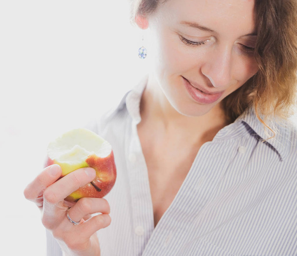 Щасливі молода жінка їсть яблуко, білий фон - Фото, зображення