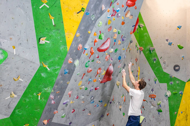 climber explores and develops a route on a climbing wall in the boulder hall - Foto, immagini