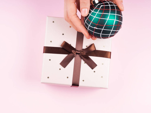 Womans hand holding christmas bauble. Gift box - Φωτογραφία, εικόνα
