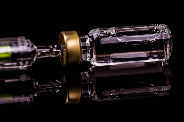 Ampola e agulha de uma seringa médica sobre fundo preto
 - Foto, Imagem
