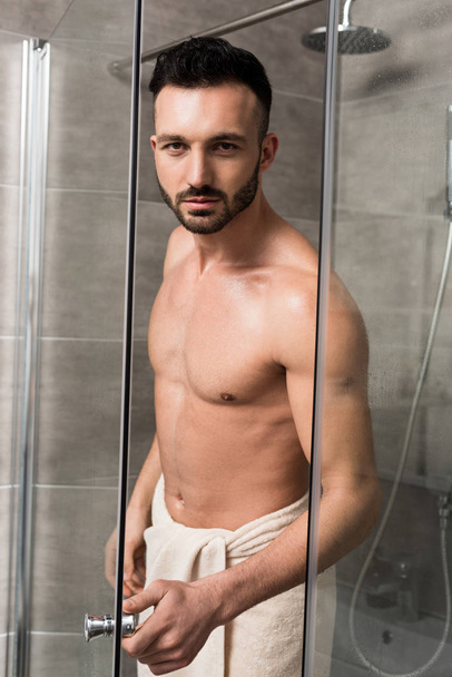 μυϊκή όμορφος άνδρας στέκεται στην καμπίνα ντους στο μπάνιο  - Φωτογραφία, εικόνα