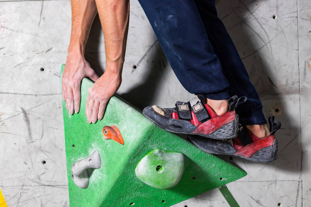 βραχώδη παπούτσι σε ένα μικροσκοπικό, λιγοστά snare στέκεται με την άκρη του κάλτσα σε close-up τοίχος αναρρίχησης στο δωμάτιο - Φωτογραφία, εικόνα