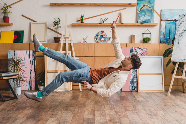 handsome artist levitating over wooden floor in gallery - Photo, Image