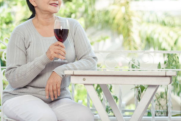 屋外カフェでテーブルに座ってワインのグラスと高齢女性の画像をトリミング - 写真・画像