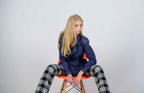 Fashionable coat. Clothes and accessory. Mixing styles. Girl fashion model wear coat for spring season. Trench coat fashion trend. Must have concept. Woman makeup face posing coat at modern chair - Foto, Bild