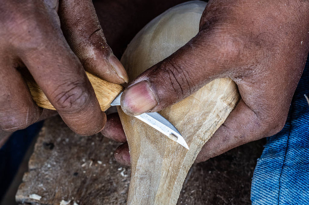 houtbewerker die met handgereedschap bewerkt houten lepel met houtsnijmessen - Foto, afbeelding