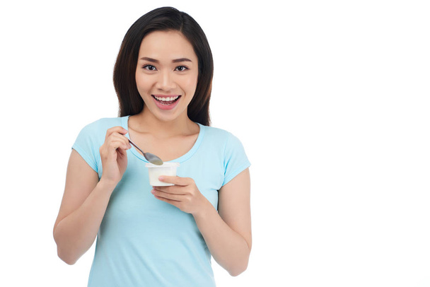 Attractive young Vietnamese woman eating yogurt, isolated on white - Foto, Bild