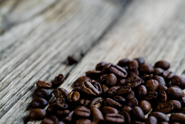 Hromadu pražených kávových zrn na dřevěný stůl - Fotografie, Obrázek