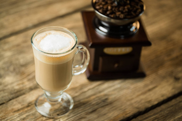 винтажная кофемолка с жареными кофейными зернами и чашкой кофе на деревянном столе
 - Фото, изображение