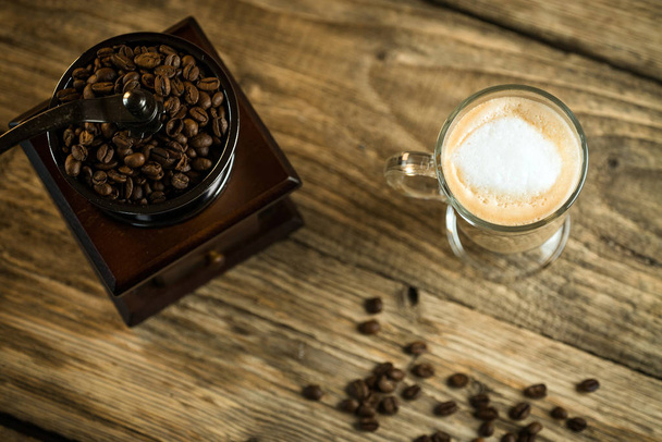 Vintage-mlýnek na kávu s pražená kávová zrna a šálek kávy na dřevěný stůl - Fotografie, Obrázek