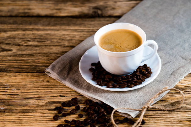 кучка жареных кофейных зерен и чашка кофе на деревянном столе
 - Фото, изображение