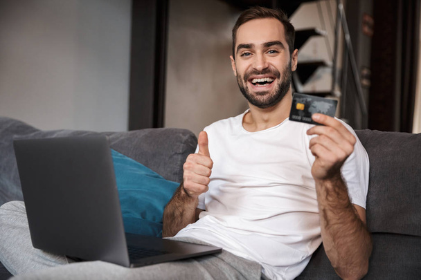 Happy young man sitting on a couch - Photo, image