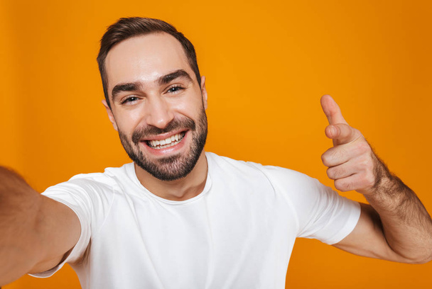 Portrait of optimistic man 30s in t-shirt laughing while taking  - Φωτογραφία, εικόνα