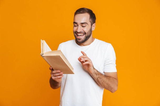 Image of attractive man 30s in white t-shirt holding and reading - Foto, afbeelding