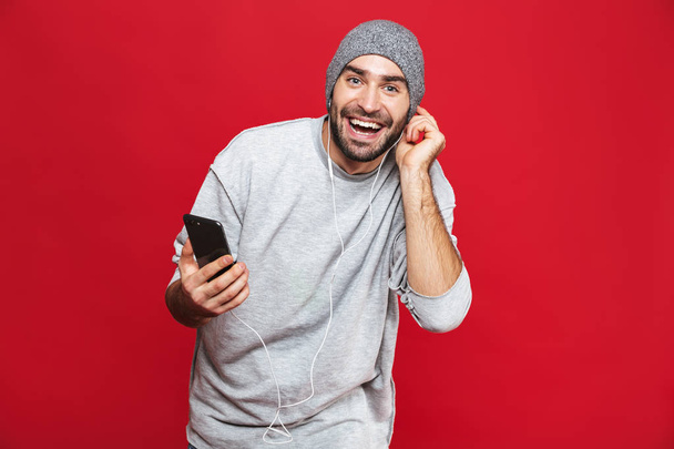 Image of attractive man 30s listening to music using earphones a - Foto, Imagen