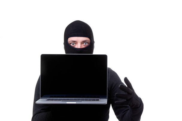 Hombre ladrón en máscara negra con portátil con pantalla en blanco en las manos
. - Foto, imagen
