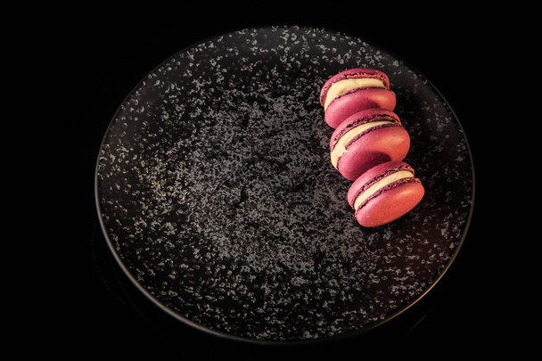 top view three purple berry macaroons served on black plate - Photo, image