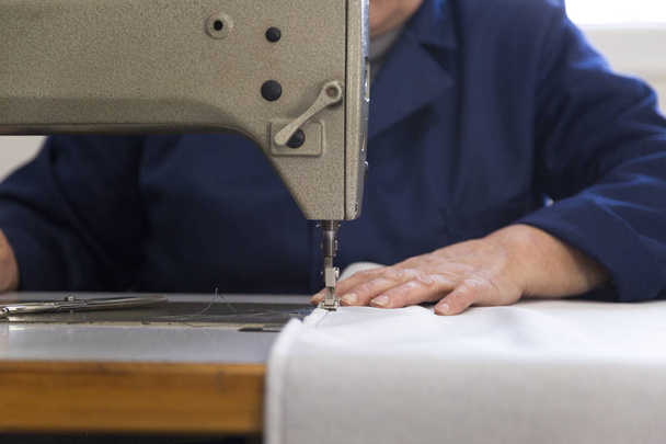 Closeup of an older woman in a furniture factory who is sewing the material for the sofa - Foto, Imagem