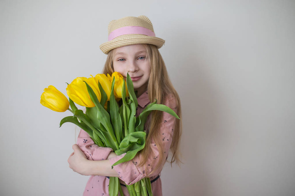 Tini lány rózsaszín ruhában, nagy csokor sárga tulipán - Fotó, kép