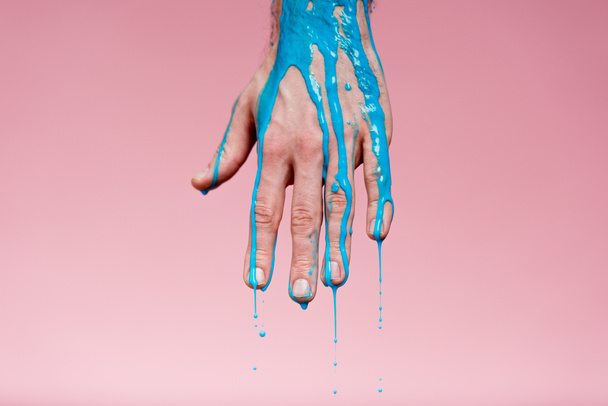 recortado con de mano masculina con derrames de pintura azul sobre rosa
 - Foto, Imagen