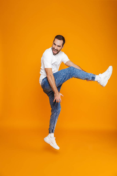 Full length photo of optimistic guy in t-shirt and jeans jumping - Foto, imagen