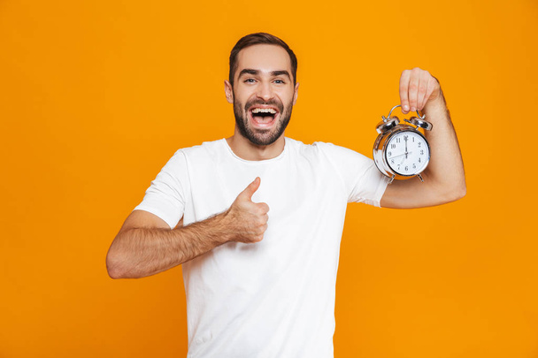 Photo of optimistic man 30s in casual wear holding alarm clock,  - Fotoğraf, Görsel