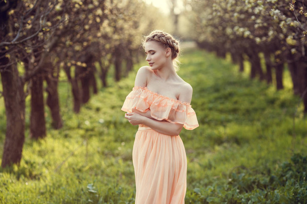 Bella ragazza in un vecchio vestito in un giardino fiorito di pere
. - Foto, immagini