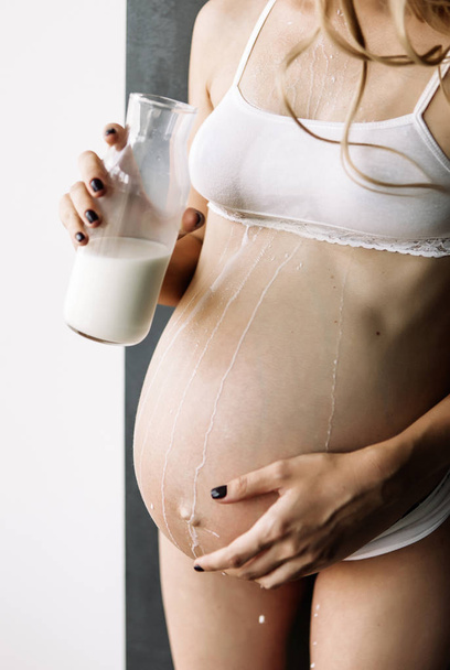 fille enceinte en sous-vêtements blancs boit du lait d'une bouteille et se déverse sur elle-même
 - Photo, image