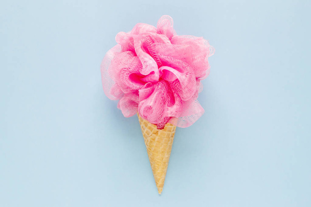 Composición de cono de helado con mechón rosa sobre un fondo azul claro. Accesorios cosméticos de baño. Lay plana. Vista superior
 - Foto, imagen