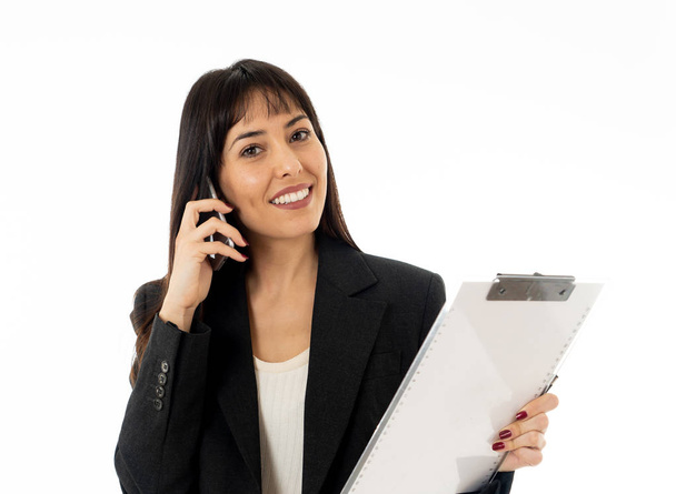 Half length portrait of young smiling beautiful businesswoman with folder speaking on mobile smart phone feeling confident and successful. In people, business, communication and technology concept. - Foto, afbeelding