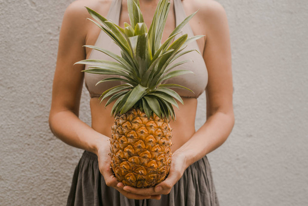 woman in boho clothes keep the tropical fruit pineapple in hands - Fotó, kép