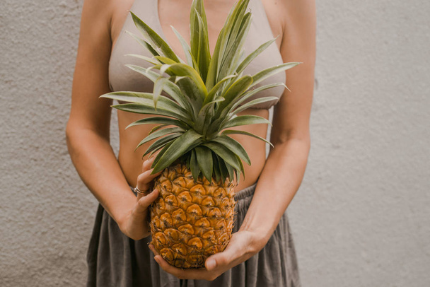 woman in boho clothes keep the tropical fruit pineapple in hands - Foto, afbeelding