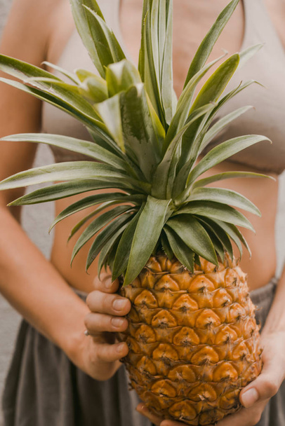 woman in boho clothes keep the tropical fruit pineapple in hands - Foto, Imagem