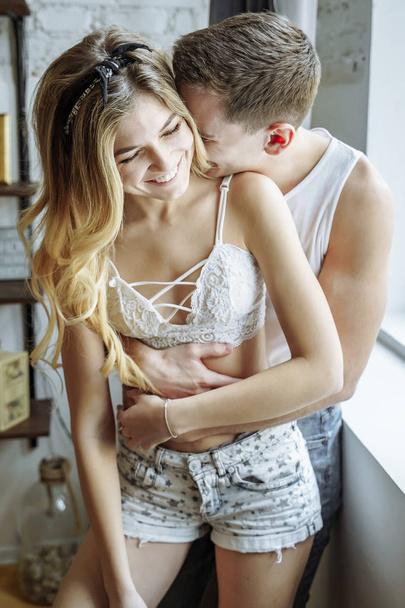 Happy moments together. Happy young couple embracing and smiling at home. - Fotó, kép