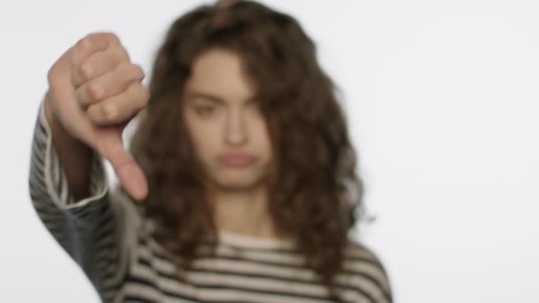スタジオで親指を立てている悲しい女の子。サインの手が嫌いな動揺した女性 - 映像、動画