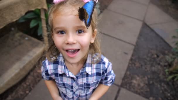 Dívka je velmi šťastný a s úsměvem, protože Krásný motýl přistál na hlavě. 4 k pomalé Mo - Záběry, video