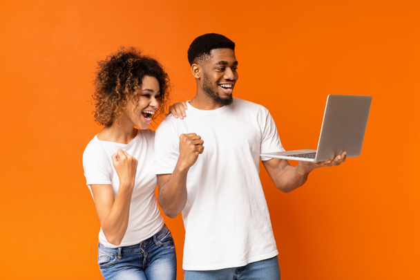 Ενθουσιασμένο μαύρο ζευγάρι γιορτάζει νίκη με φορητό υπολογιστή - Φωτογραφία, εικόνα