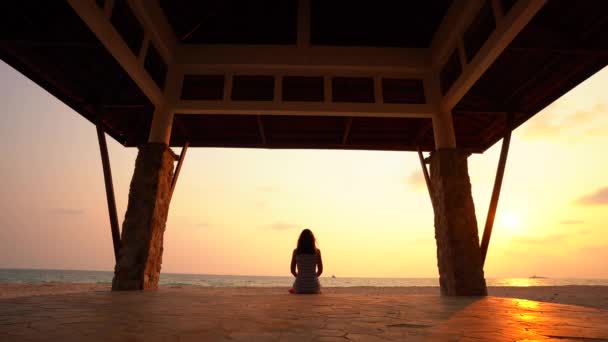 Het meisje is het maken van yoga vormen in een boeddhistische tempel bij zonsondergang. - Video