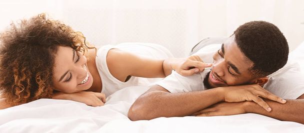 fröhliche Frau, die ihrem Mann die Nase im Bett berührt - Foto, Bild