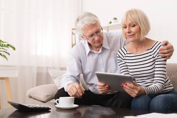 Casal de idosos usando tablet digital na sala de estar
 - Foto, Imagem