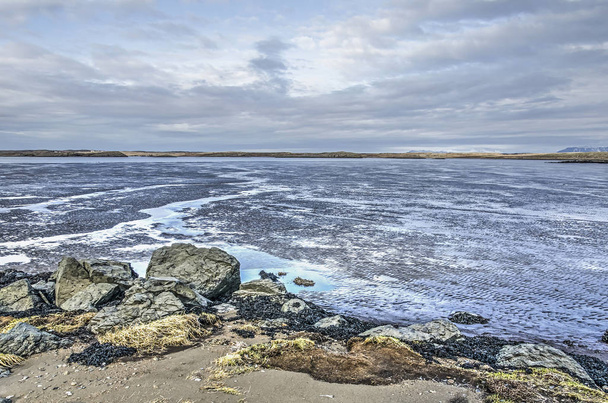 Grandes roches et surfaces sablonneuses sur une plage près de Borgarnes, en Islande, avec vue sur les vasières à marée basse sous un ciel spectaculaire
 - Photo, image