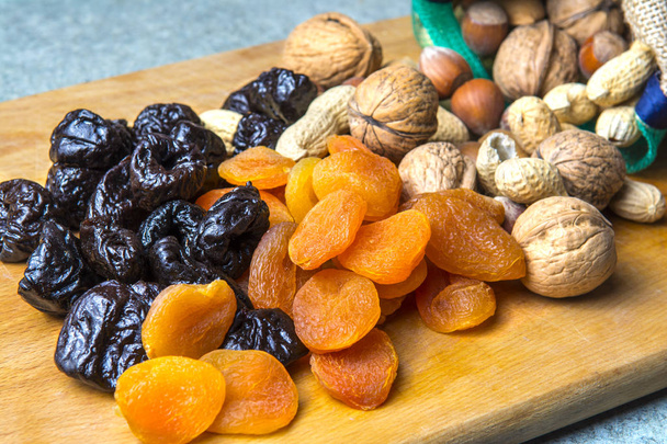 vegetarian food of nuts and dried fruits on the kitchen board - Photo, Image