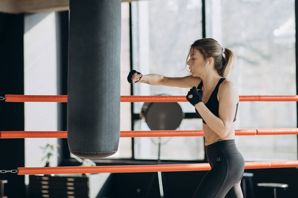 Beautiful Woman training punching bag in fitness studio fierce strength fit body - Zdjęcie, obraz
