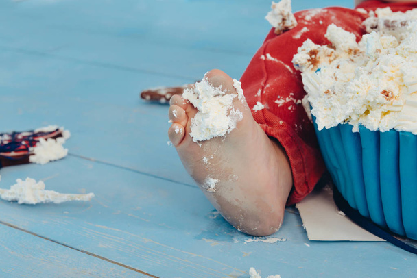 decoration for the boys birthday, smash the cake in a nautical marine style. stylized birthday ship photo shoot. leg cheerful funny boy eats and break a cake with his hands on the first holiday - Photo, image