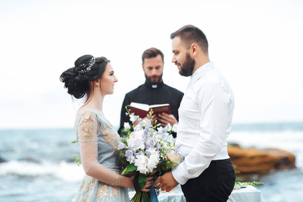 couple de mariage sur l'océan avec un prêtre - Photo, image