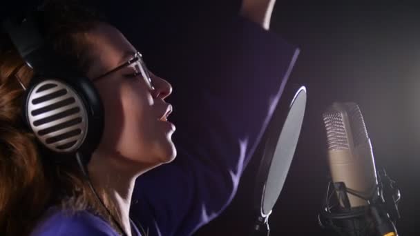 Een emotionele jonge vrouw in een bril het opnemen van een lied in de Studio - Video