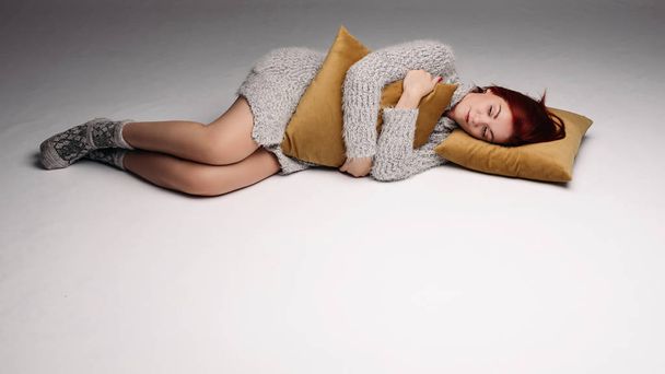 Portrait studio d'une femme en pull serrant un oreiller
. - Photo, image